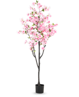 De Kunst Kersenbloesem 180 cm roze heeft roze bloesems en groene bladeren in een kleine zwarte pot, tegen een effen witte achtergrond.