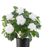 De Kunstplant Gardenia UV 39 cm wit heeft weelderige groene bladeren en grote witte gardeniabloemen in een eenvoudige zwarte pot, tegen een effen witte achtergrond.