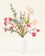 In een vaas met witte structuur staat het Zijden kunstbloemen boeket Featherlight Florals met zachtroze en diepmagenta zijden bloemen, plus groene eucalyptusbladeren op lange stelen, tegen een lichte achtergrond.