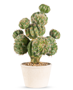 De Kunst Cactus 32 cm heeft een groene, ronde cactus met stekels in een pot van wit keramiek gevuld met kleine steentjes tegen een lichtgrijze achtergrond.