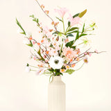 Een crèmekleurige vaas toont het Zijden kunstbloemen boeket Pink & Pearl, met delicate roze, witte en perzikkleurige zijden bloemen met groene bladeren tegen een licht neutrale achtergrond.