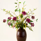 In een bruine, geribbelde vaas staat het boeket „Woodland Charm“ van Zijden kunstbloemen, met paarse alliums, donkerroze bloemen, gele takjes en groen blad tegen een effen, lichte achtergrond.