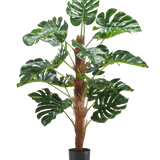 De Kunstplant Monstera 120 cm is een kunstplant in pot met grote, glanzende groene bladeren en een bruine stengel met textuur tegen een effen witte achtergrond.