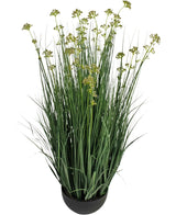 De Kunstgras Prei Bloem Ui Graspot 100cm brandvertragend heeft lange, slanke groene grasachtige bladeren en kleine geelgroene bloemtrosjes in een ronde zwarte pot, tegen een witte achtergrond.