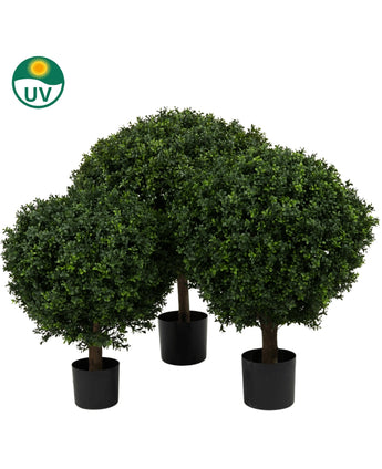 De Kunstplant Buxus op stam romeinse stijl UV 85cm heeft drie kunstmatige buxusbomen in zwarte potten met dicht, rond groen gebladerte, tegen een witte achtergrond met een UV-beschermingssymbool in de linkerbovenhoek.