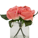 De Kunstrozenboeket Real Touch Roze 18cm heeft vier roze kunstrozen met groene bladeren, gerangschikt in een kleine glazen pot en tegen een witte achtergrond.