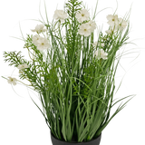 De Kunstgras witte Gesang Bloem uiengraspot (56cm, brandvertragend) heeft hoge, grasachtige groene bladeren en delicate witte bloemen in een zwarte pot voor een weelderige, natuurlijke uitstraling.