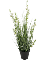 De Kunstgras Gierst Uien graspot 65cm brandvertragend heeft hoge, slanke groene grasachtige bladeren en verschillende stelen met kleine witte bloemen in een zwarte pot, tegen een effen witte achtergrond.